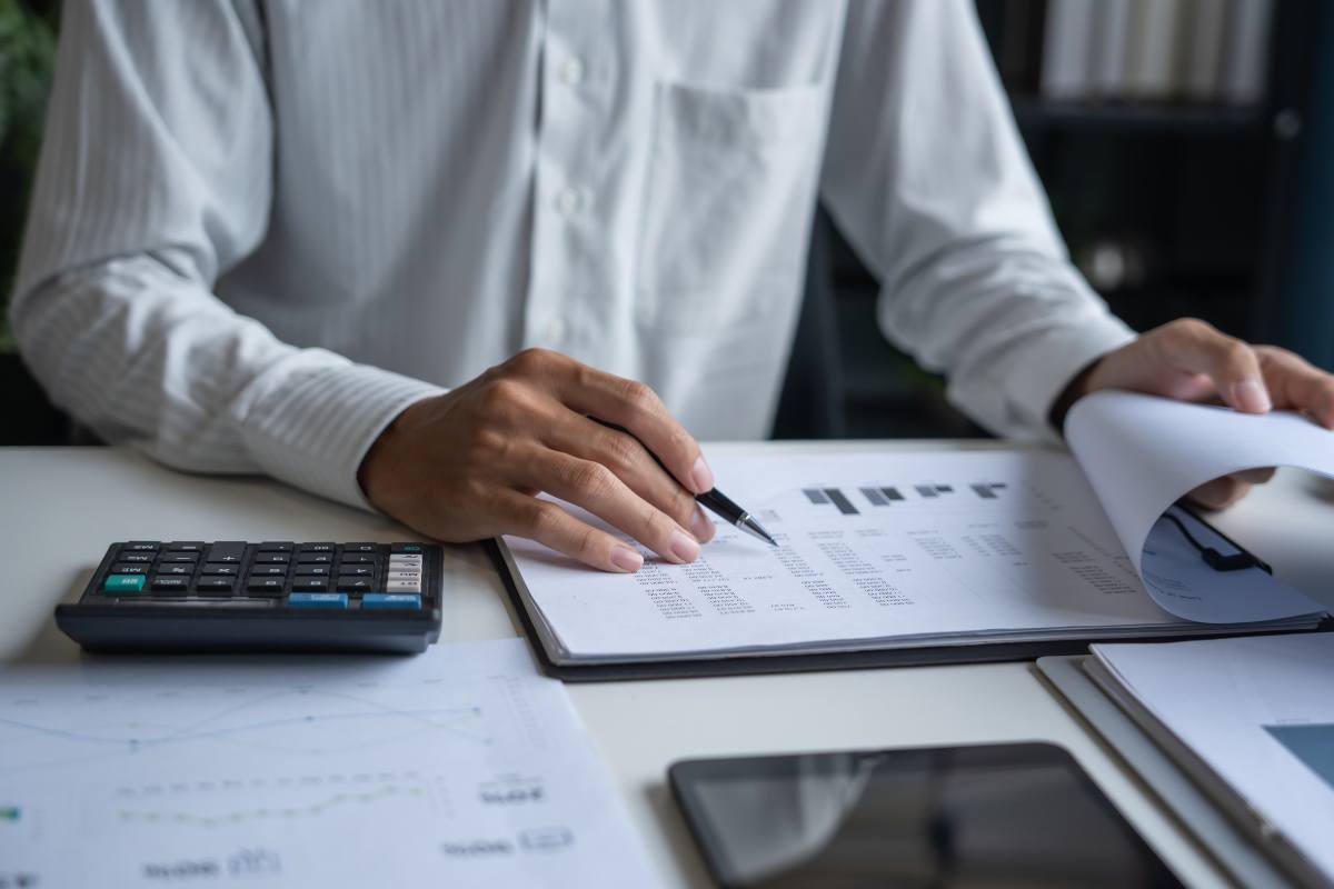 uomo che controlla fogli con calcolatrice accanto