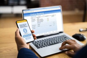 uomo con smartphone in mano e pc acceso su pagina web del conto bancario online