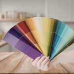 sfondo di una cucina moderna e in primo piano una mano che mantiene una palette di colori