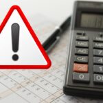 calcolatrice fogli e simbolo attenzione in rosso