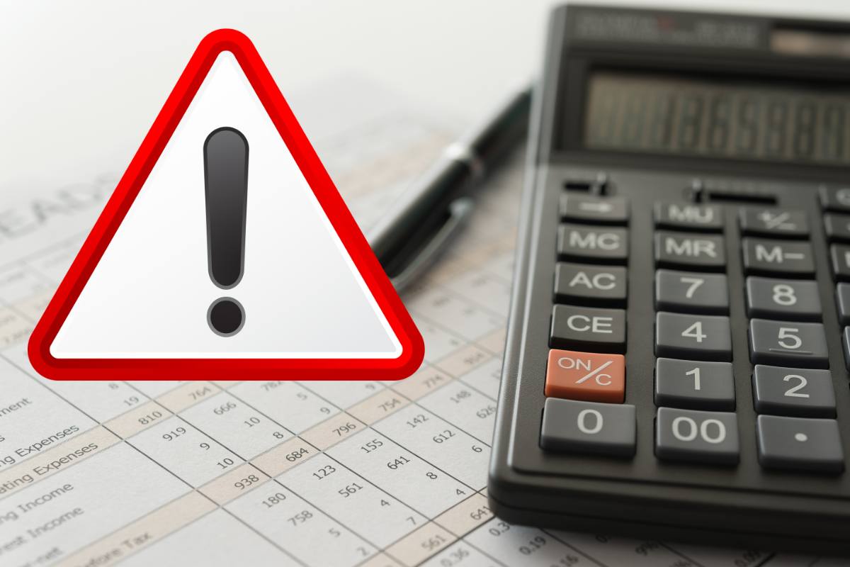 calcolatrice fogli e simbolo attenzione in rosso