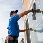 uomo pulisce finestre esterne di un edificio