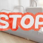 caricabatterie attaccati ad una presa multipla e scritta stop